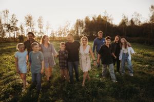 Group photo standing together in sunlit field at golden hour with trees in background.
