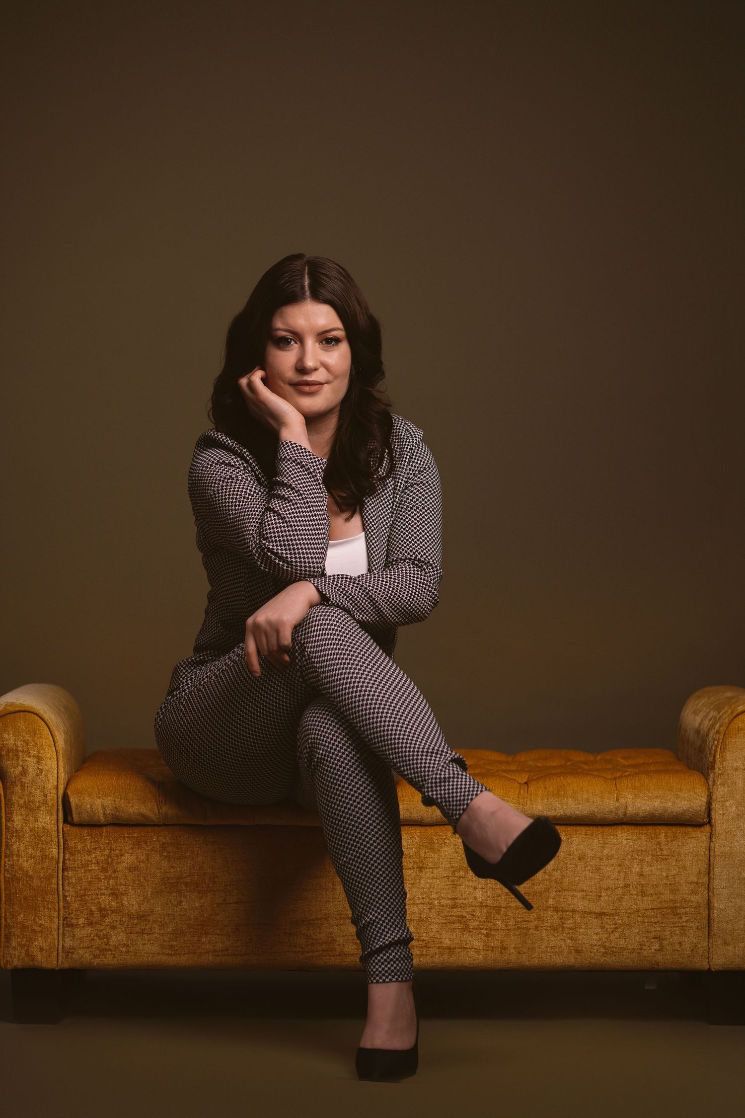 Stylish portrait series on a vintage brown leather couch in moody lighting.