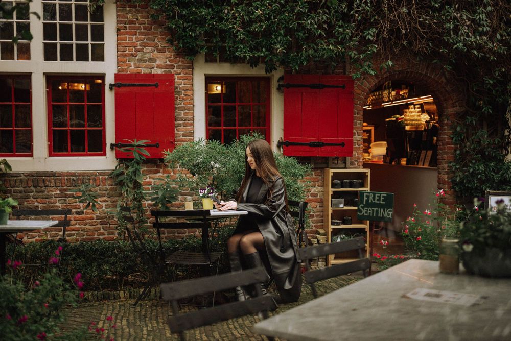 Historic brick building with red shutters and ivy-covered walls along a charming street.