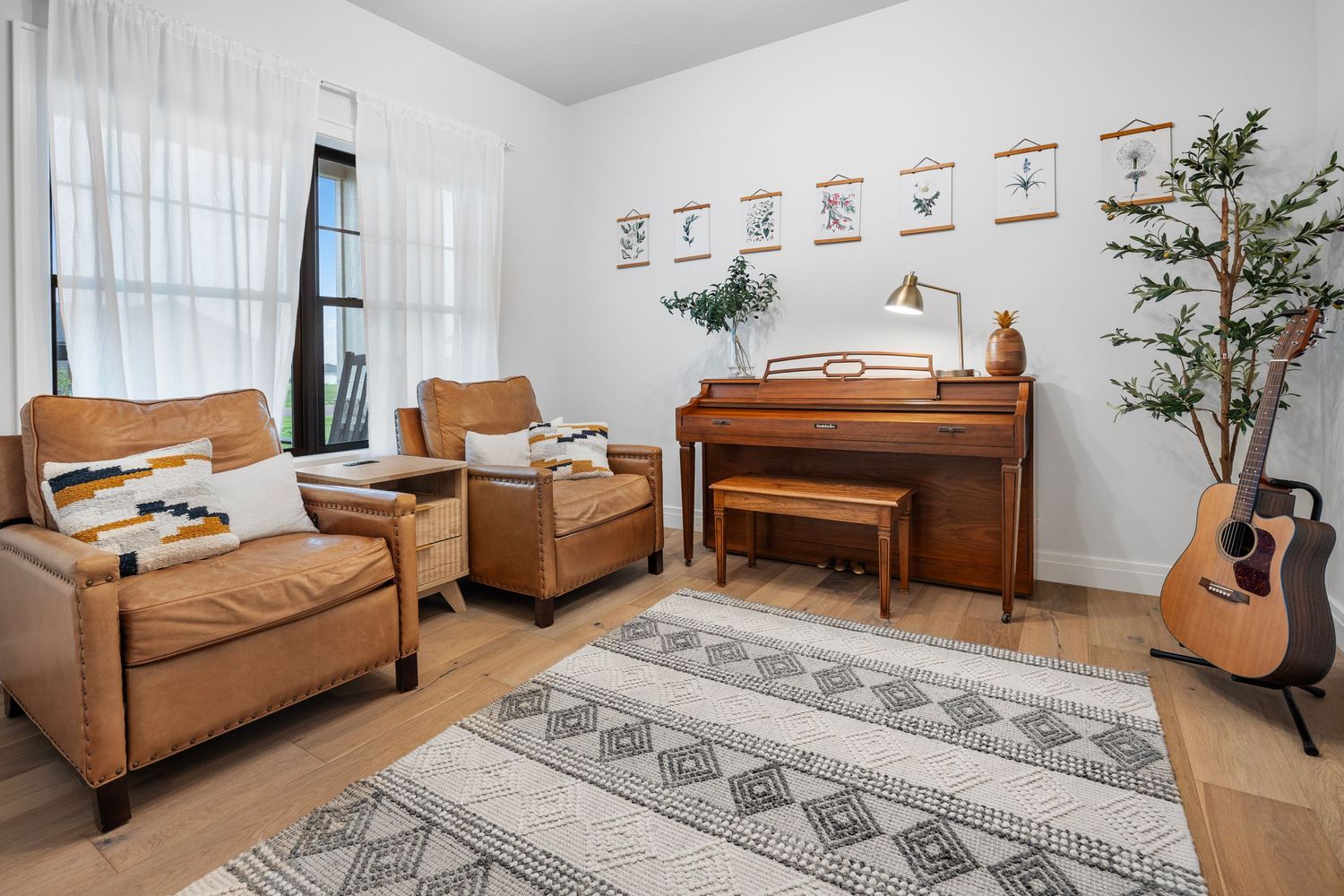 Cozy music room featuring brown leather chairs, piano, and guitar decor.