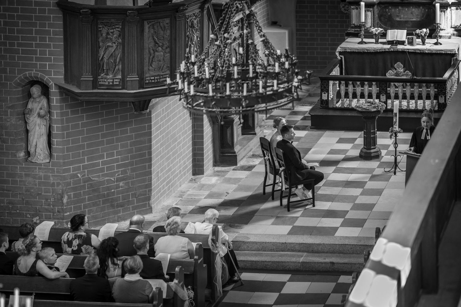 A vintage black and white photograph showing someone performing on an organ in a church sanctuary.