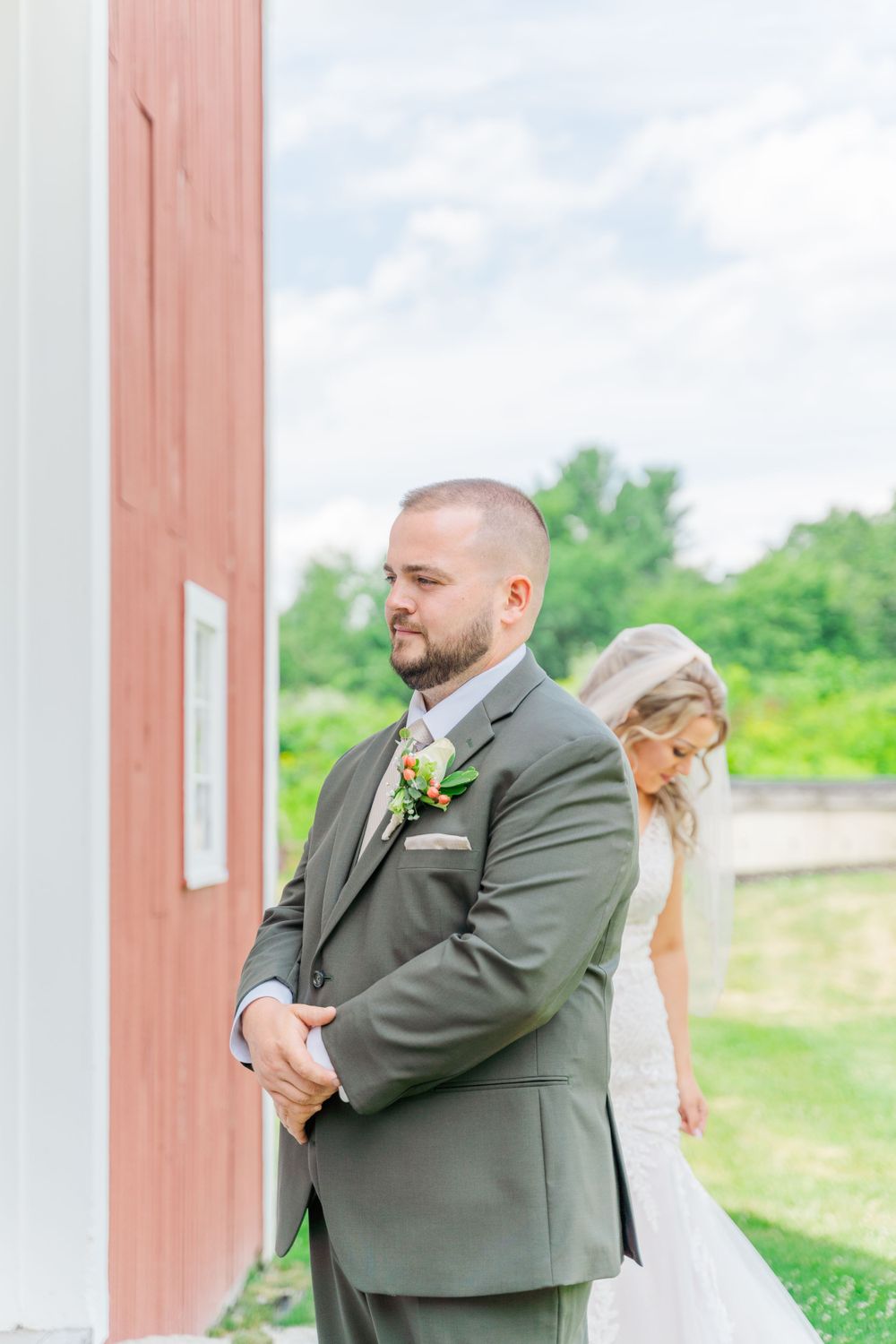 A couple shares an intimate first look moment before their wedding outside a red barn.