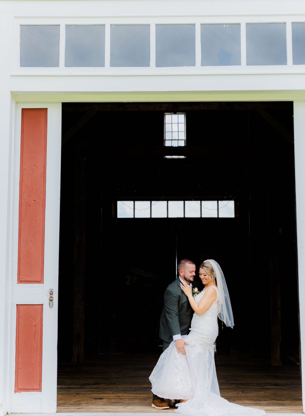 Romantic barn wedding portrait with couple silhouetted in dark doorway entrance.