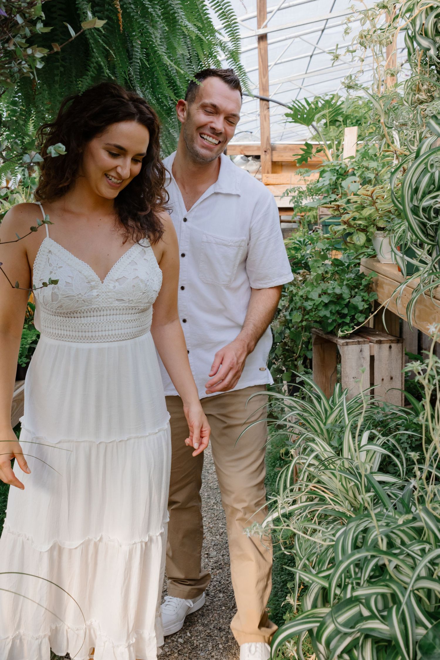 A casual couple standing together in a lush indoor garden space.
