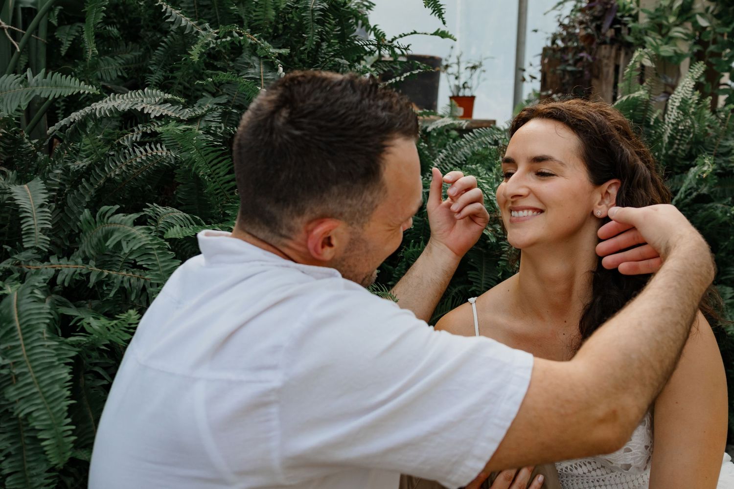Joyful candid moment captured in lush greenhouse setting.