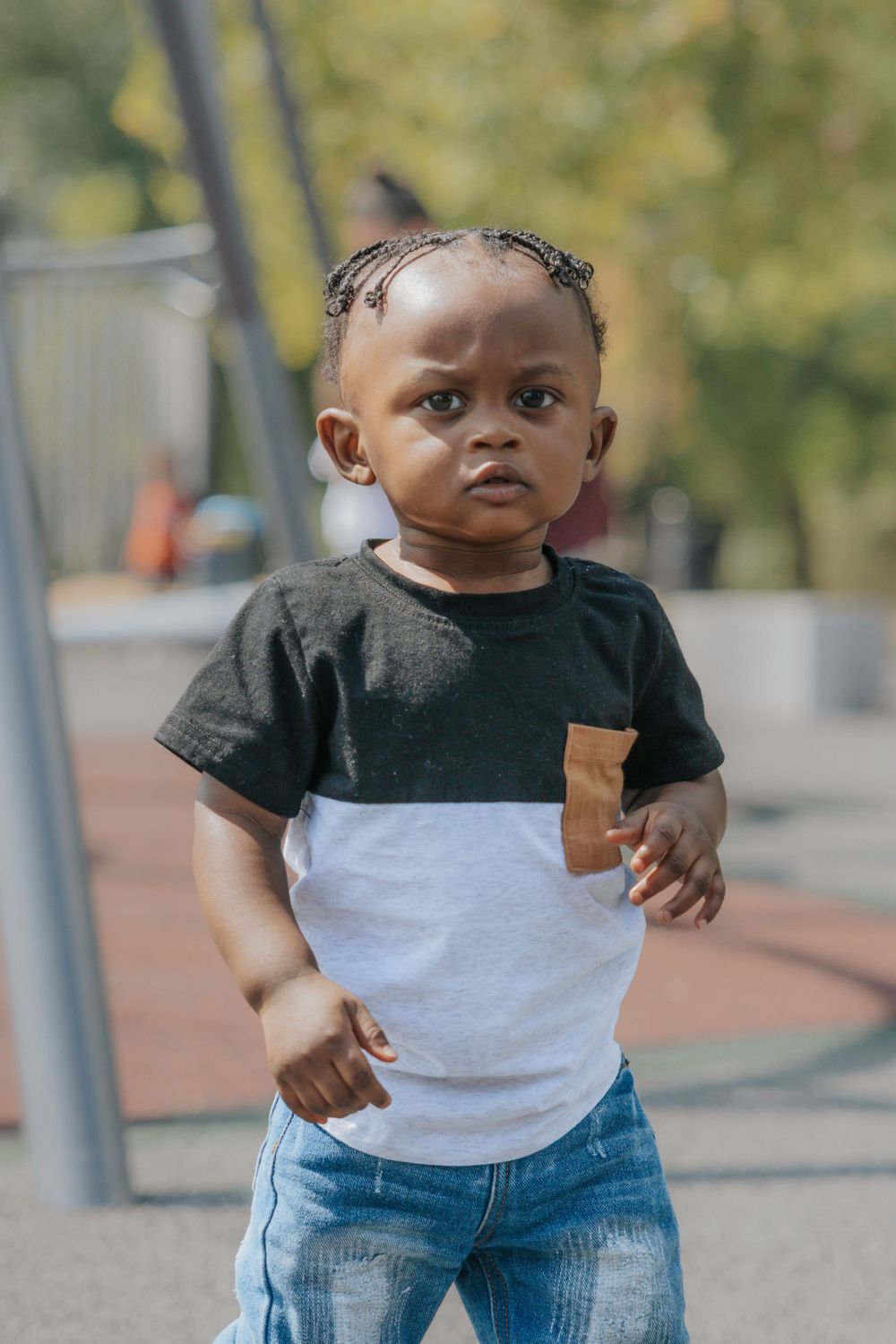 A young child wearing a black and white color block t-shirt and jeans stands outdoors.
