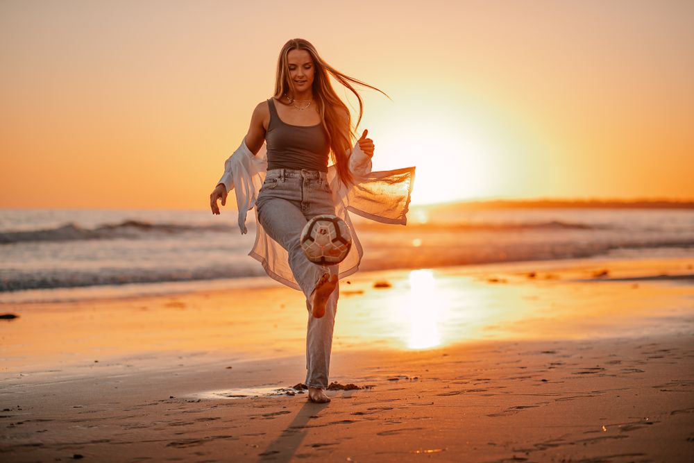 Young woman in casual outfit enjoys sunset walk on a sandy beach.