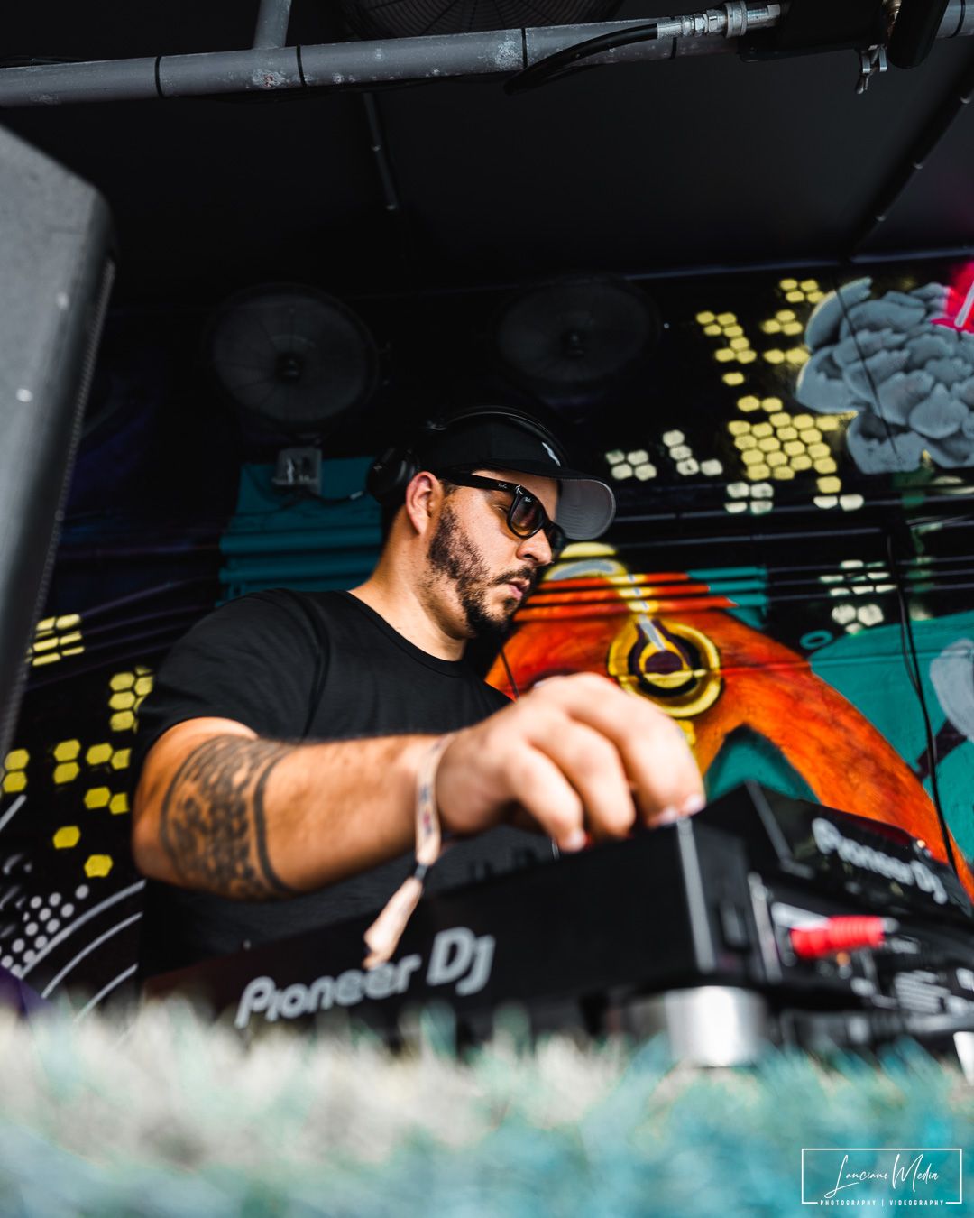 DJ performing at nightclub with Pioneer equipment under colorful lighting.