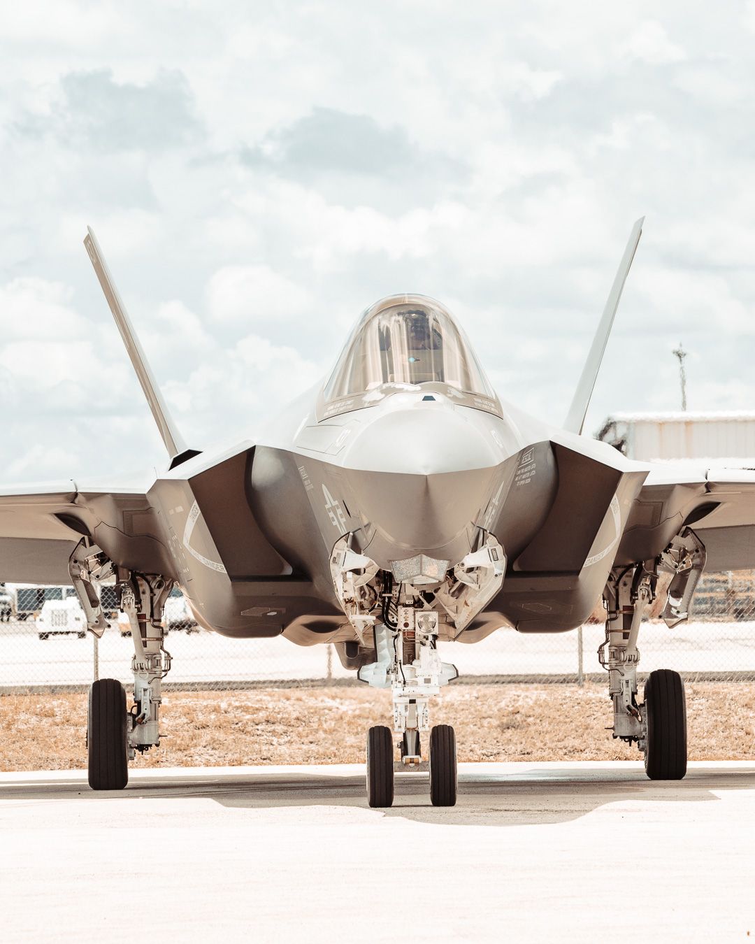 Front view of an F-35 military jet aircraft parked on tarmac showing its distinctive nose and landing gear.