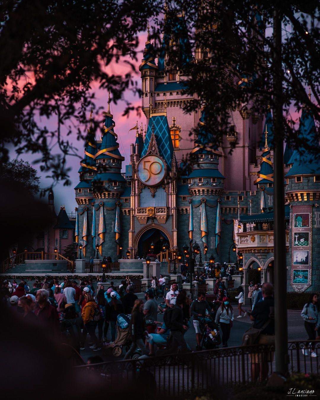 Cinderella Castle at Disney World illuminated at dusk with crowds gathered below.
