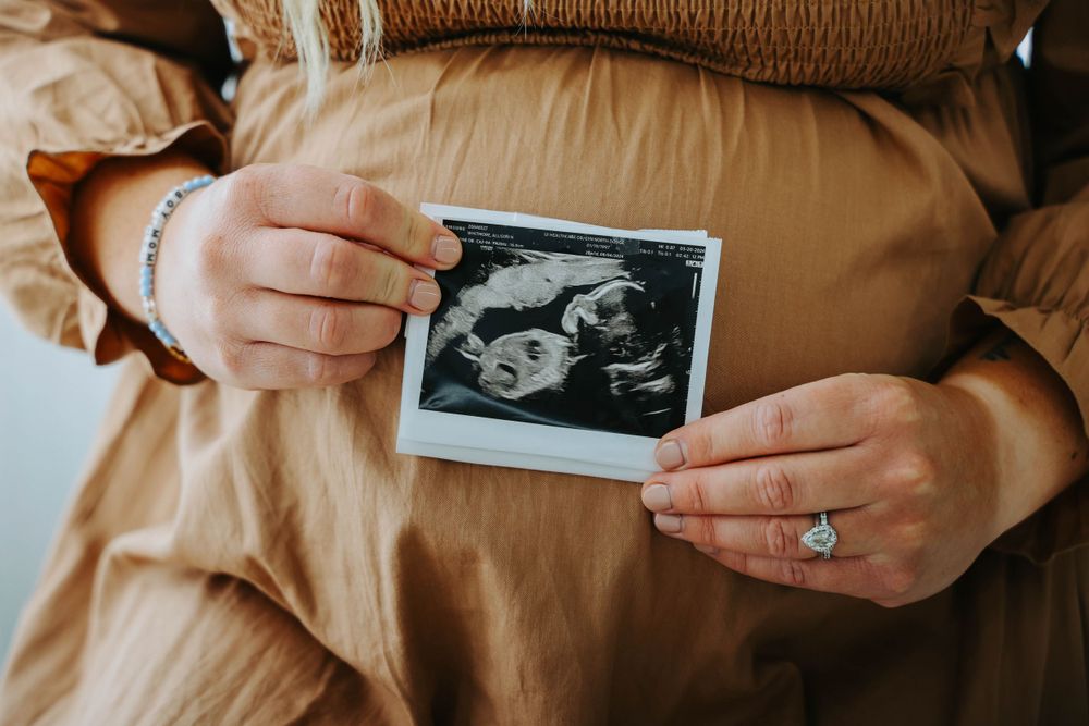 Hands holding ultrasound photo against brown maternity dress.
