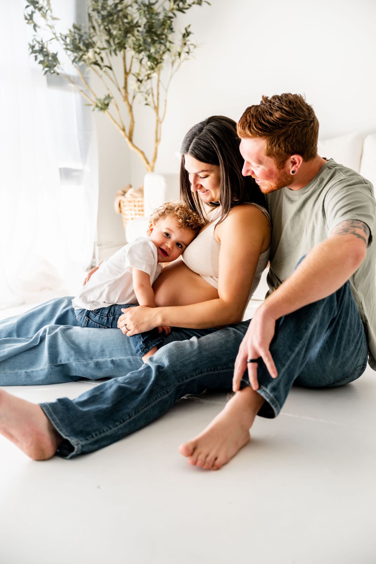 Family lying together on white floor with blue blanket in minimalist lifestyle photography session.