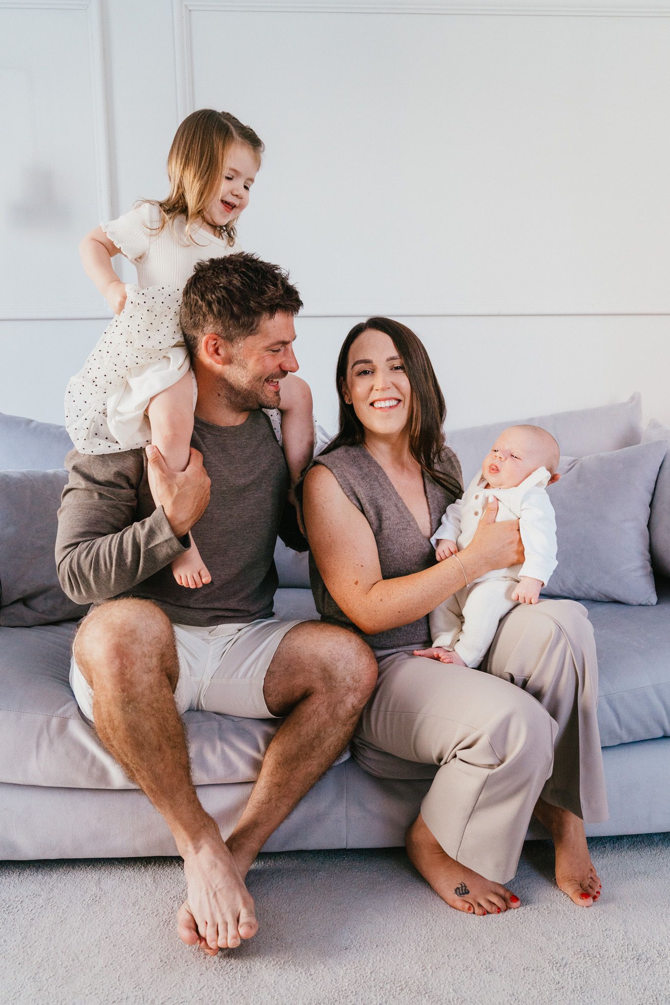 A joyful family shares a candid moment together on their gray couch.