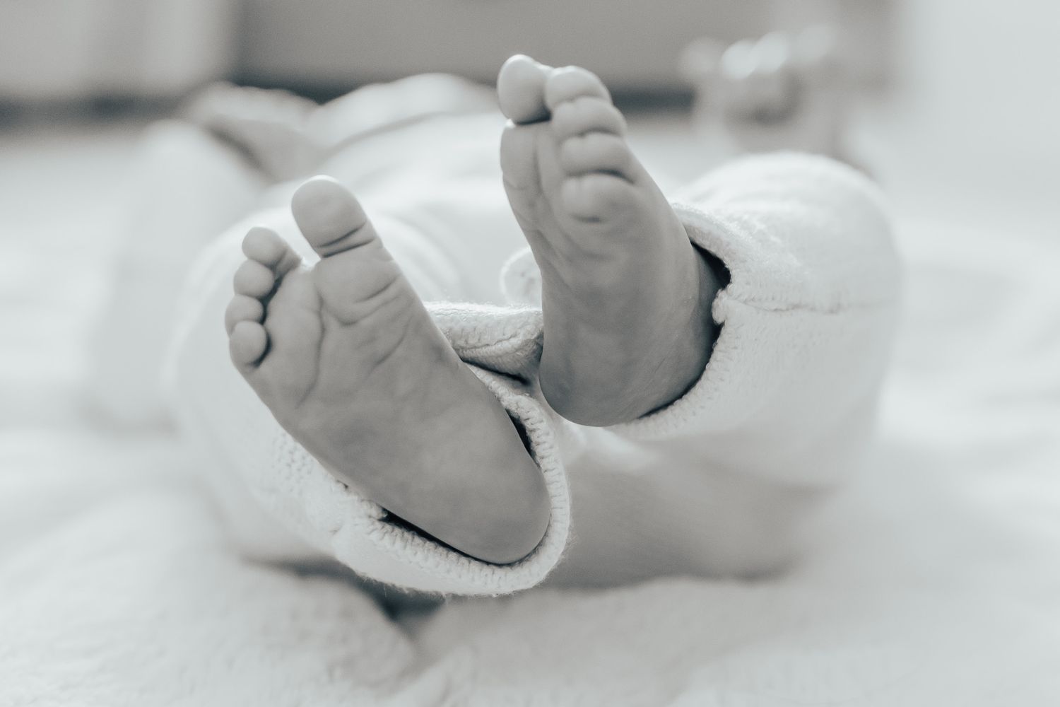 Close-up of tiny baby feet against white fabric.
