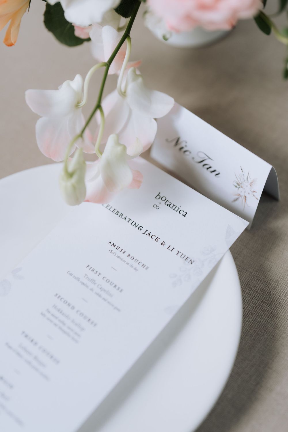 Wedding menu card with delicate pink flowers on a white plate.