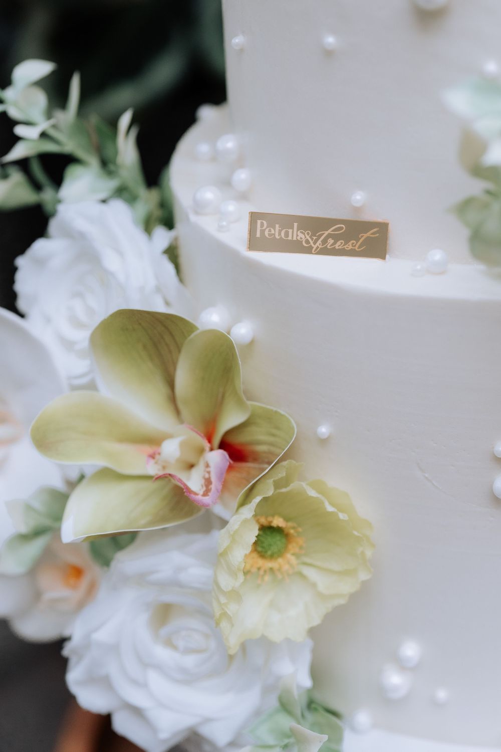 White wedding cake detail with delicate sugar flowers and pearls.