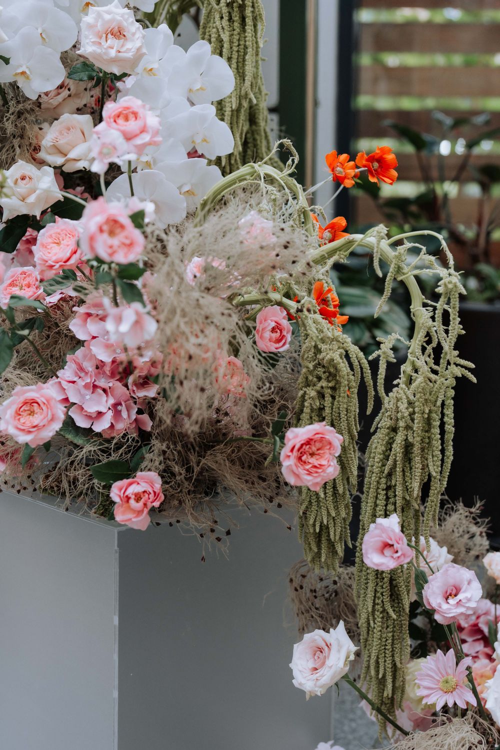 Artistic floral installation with pink roses and trailing moss creating a romantic garden aesthetic.