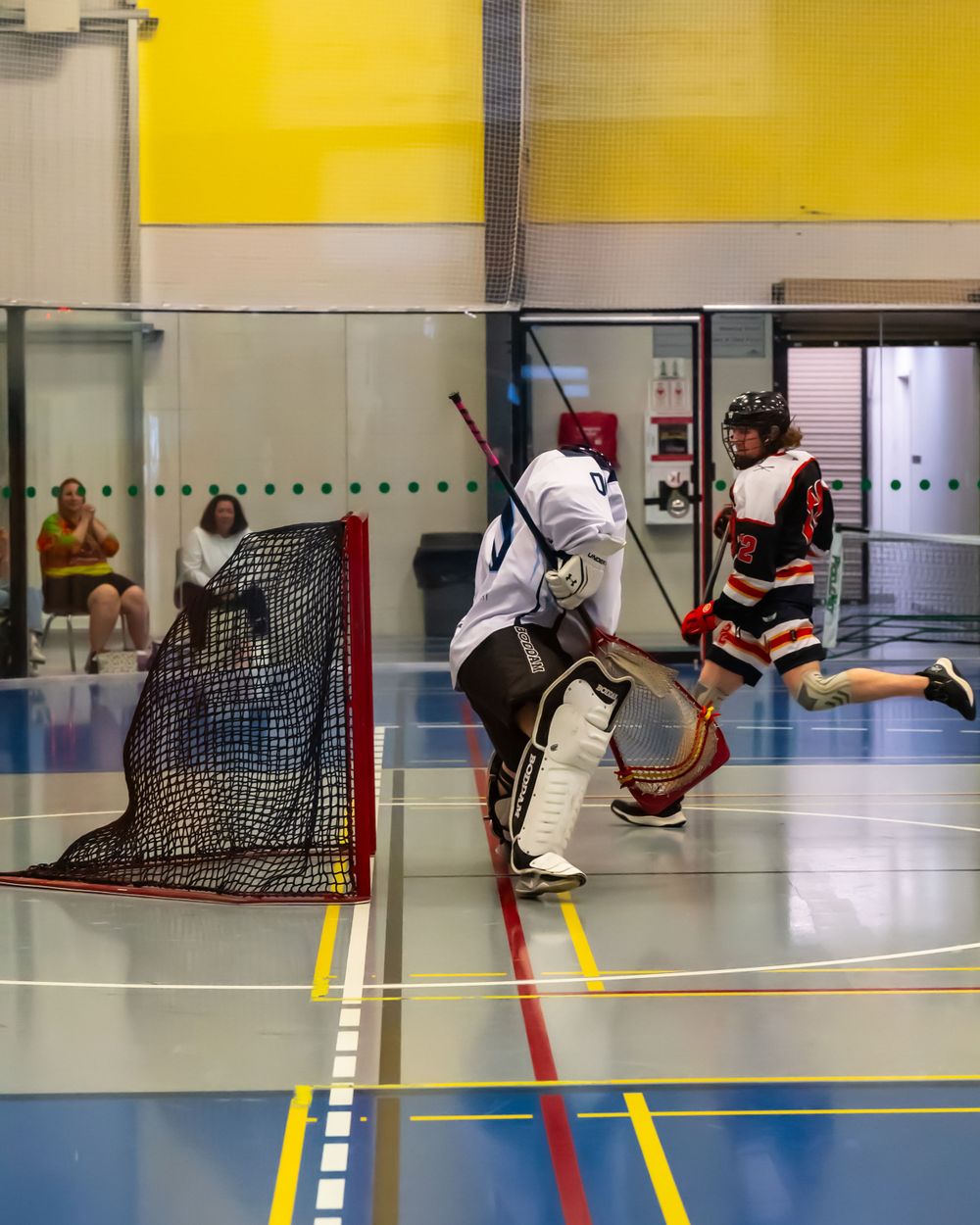 A goalie defends the net during an indoor box lacrosse game.