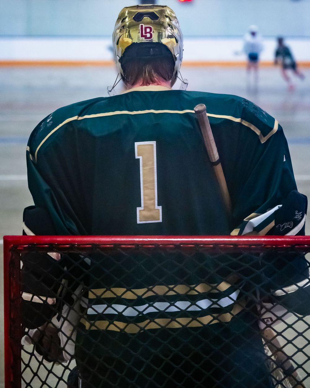 Hockey goalie wearing number 1 jersey sitting on bench during game.