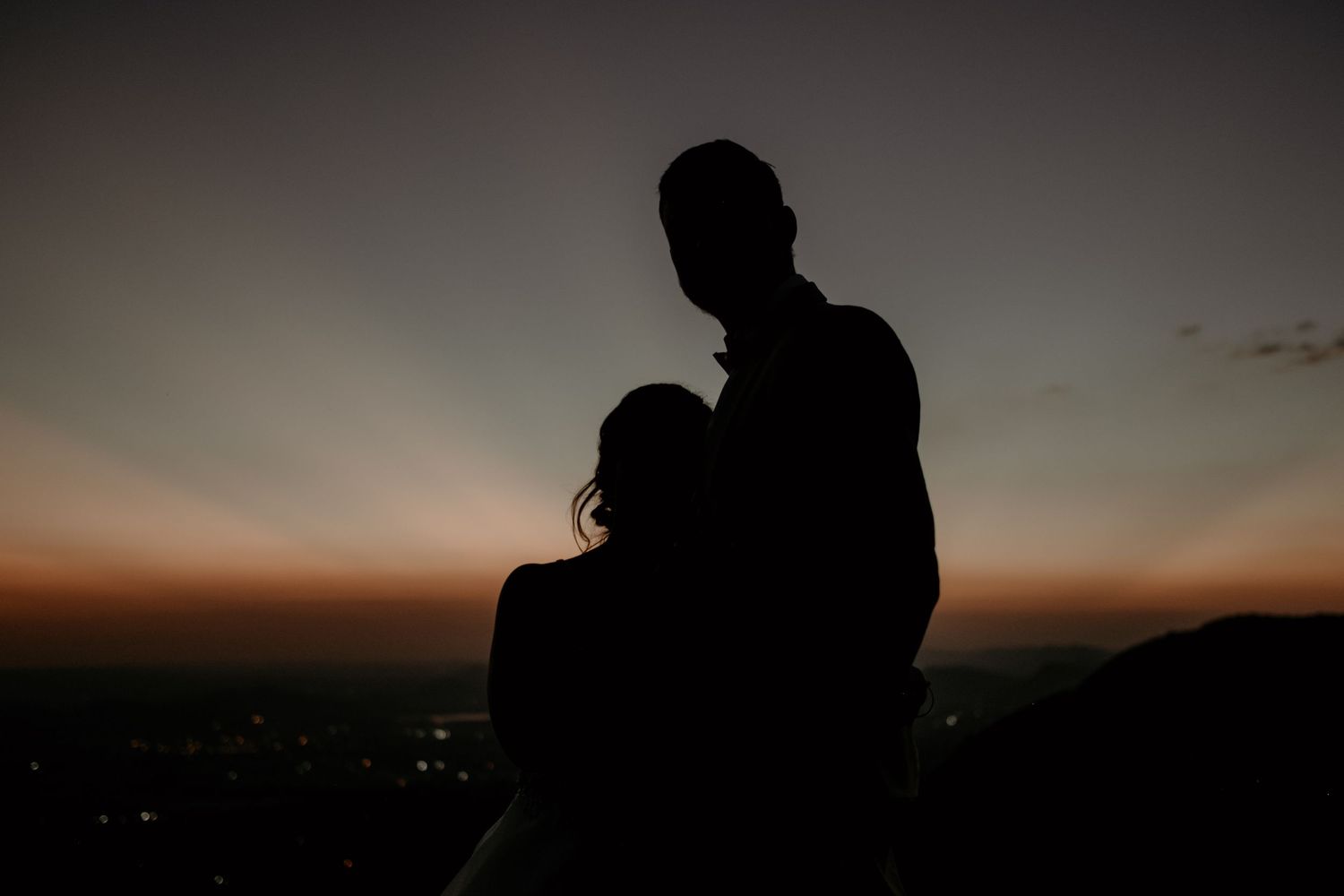 Bride and groom standing on mountain with sunset behind them during elopement wedding at Intiem Weddings Gauteng