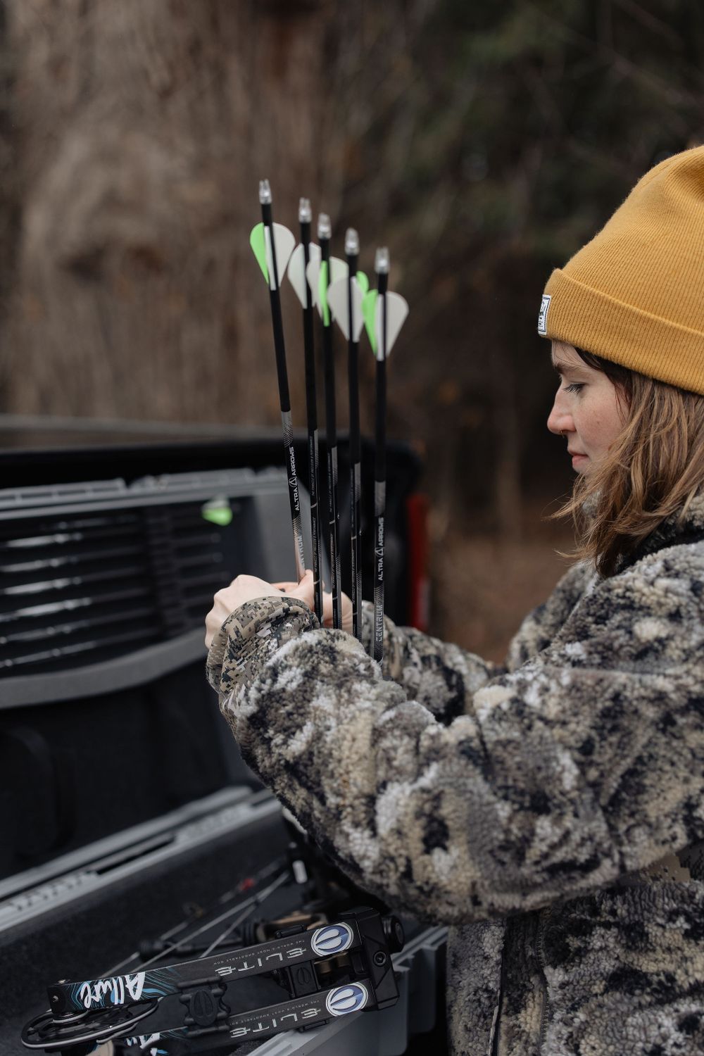 woman in camo clothing taking quiver out of archery bow case