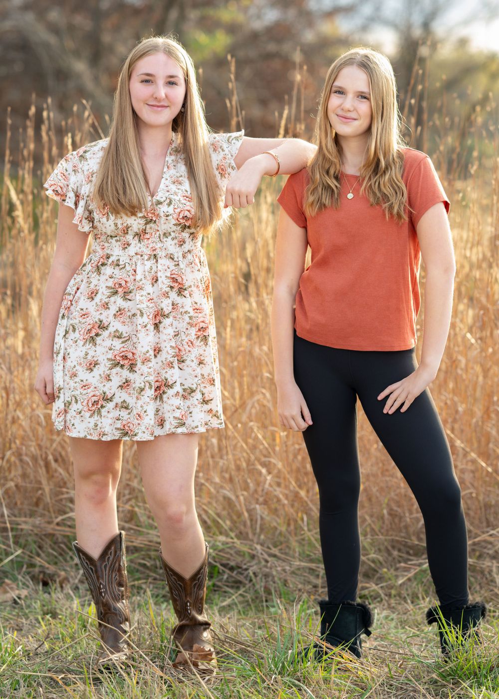 Two people pose together in field during golden hour.