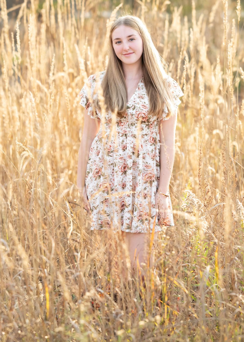 A floral dress stands out against golden wheat fields in this dreamy outdoor portrait.