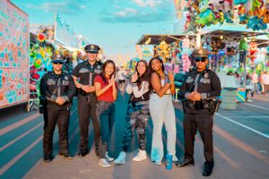 Group photo at a carnival with security officers and festive decorations.