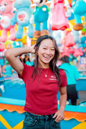 Portrait at a carnival game booth with colorful stuffed animals in the background.