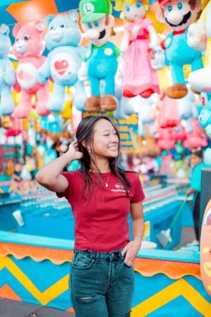Casual portrait against a vibrant display of plush video game characters at a carnival.