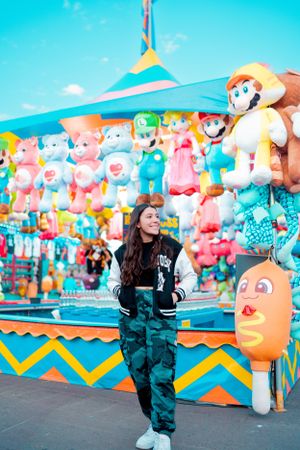 Colorful carnival game booth decorated with stuffed animals and plush toys at an amusement park.