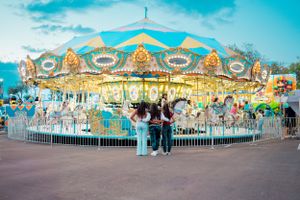 Classic carnival carousel with ornate decorations and lighting against a blue sky.
