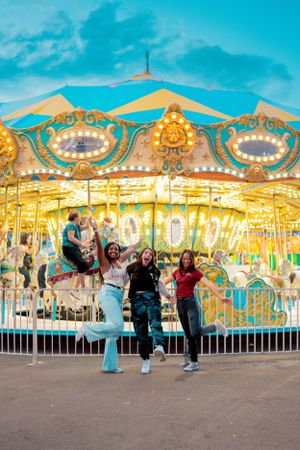 Group enjoying a moment in front of an illuminated vintage carousel at dusk.