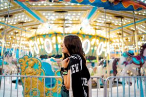 Silhouette of person standing by illuminated carousel at carnival.