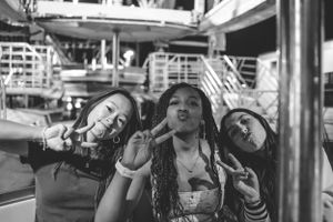 Black and white photo of friends making playful poses at an amusement park.