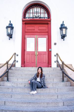 Casual style with plaid shirt and jeans on stone steps with red door backdrop.