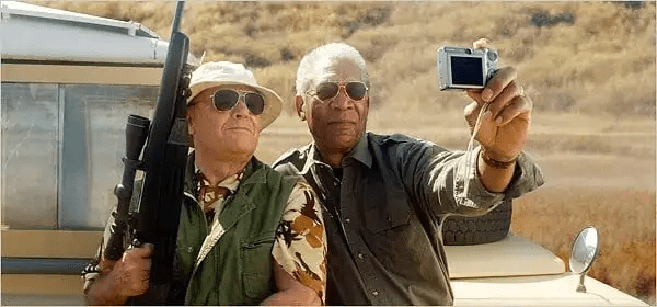 Two adventurers taking a selfie in rugged outdoor terrain while holding gear.