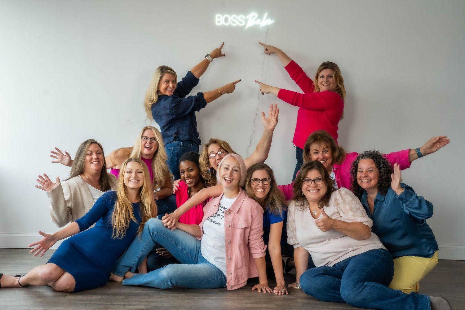 Candid group photo of women making playful poses and gestures on studio floor.
