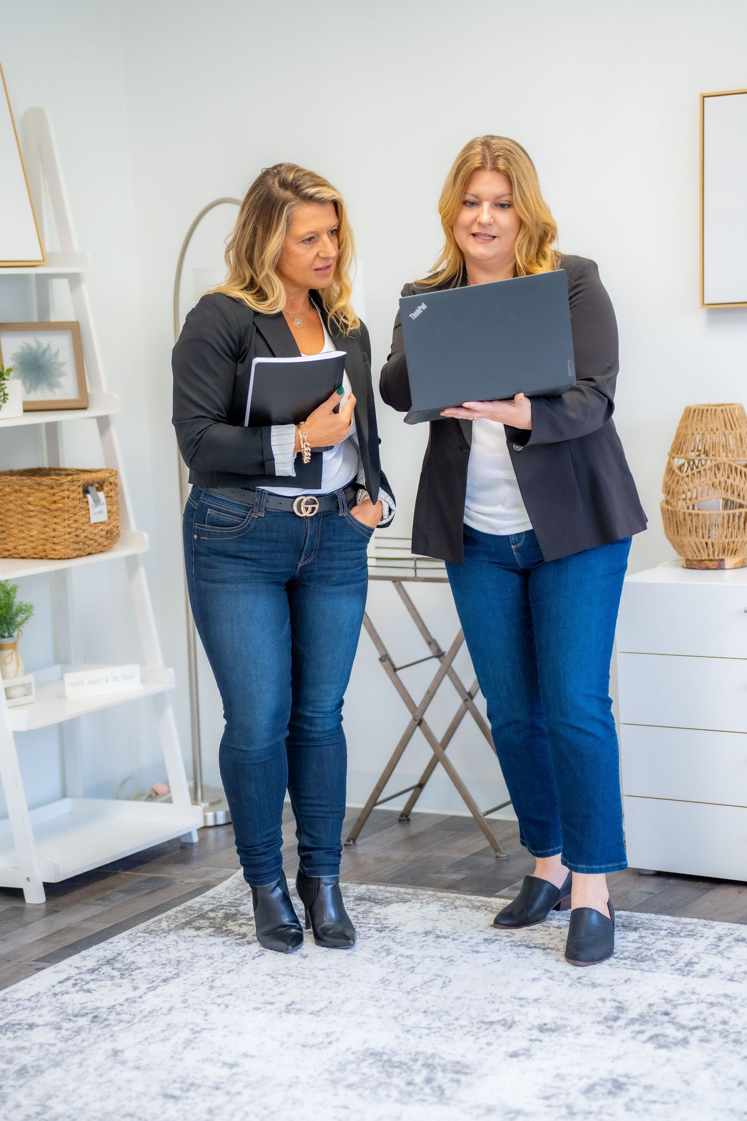 Two colleagues reviewing documents together while standing in a bright modern office space.