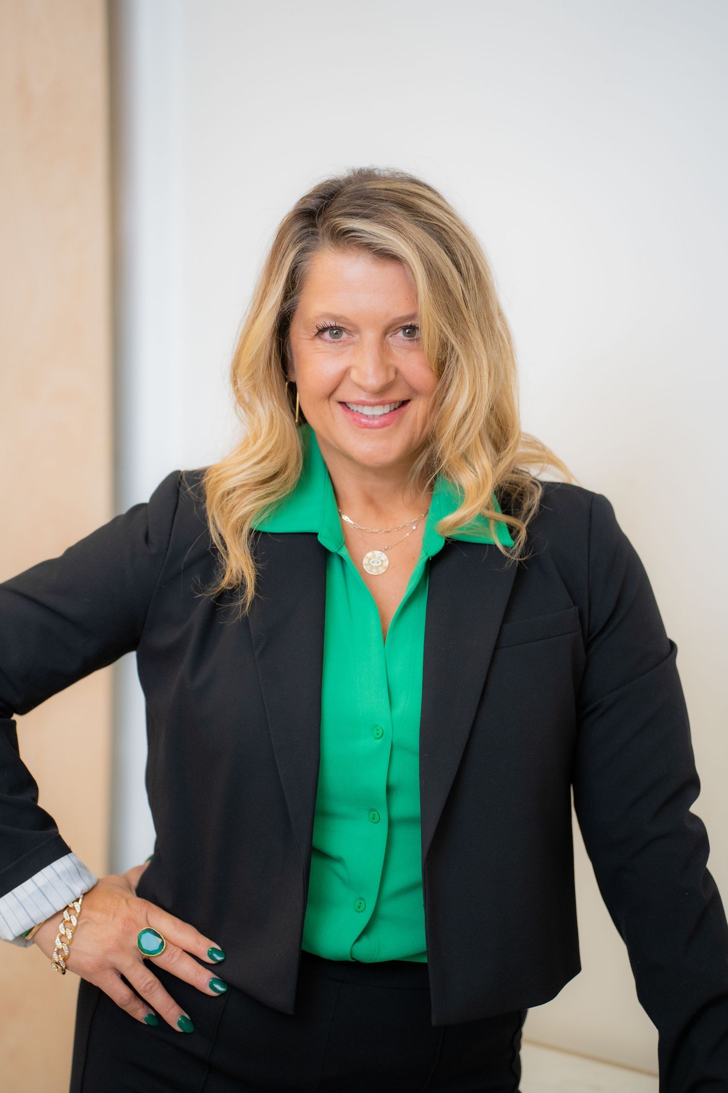 Professional woman wearing a black blazer and bright green blouse in a business setting.