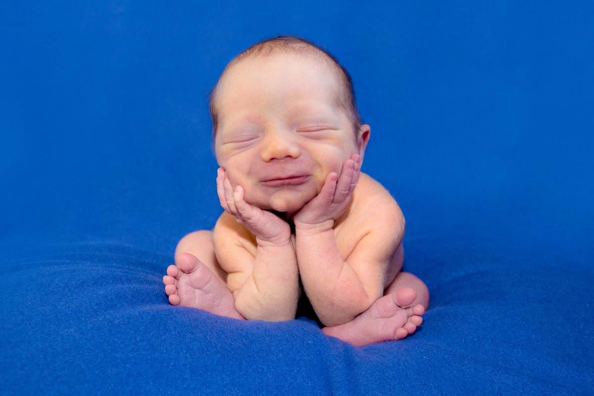 A smiling newborn baby posing with hands under chin.newborn photography
kid photography
child photography
Portrait photograph