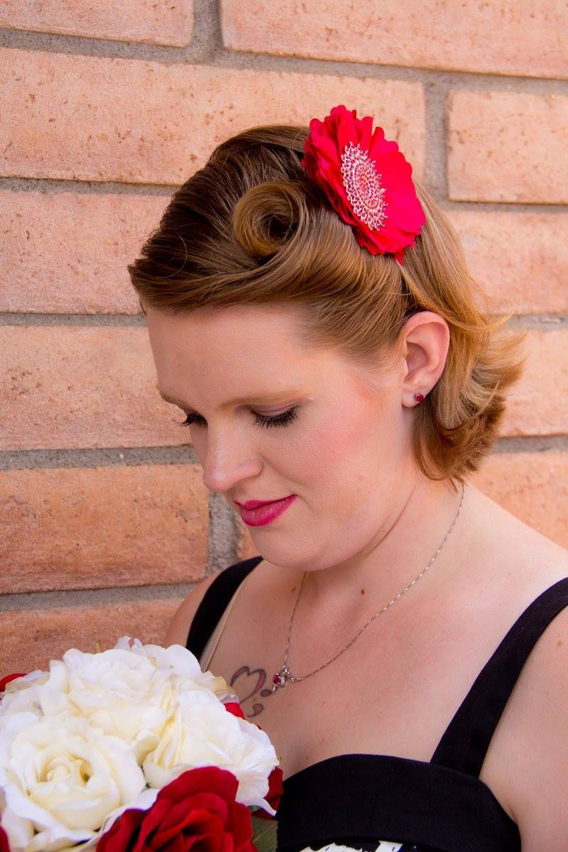 Close-up portrait showing vintage hairstyle with red flower accessory and white bouquet.
Wedding photography