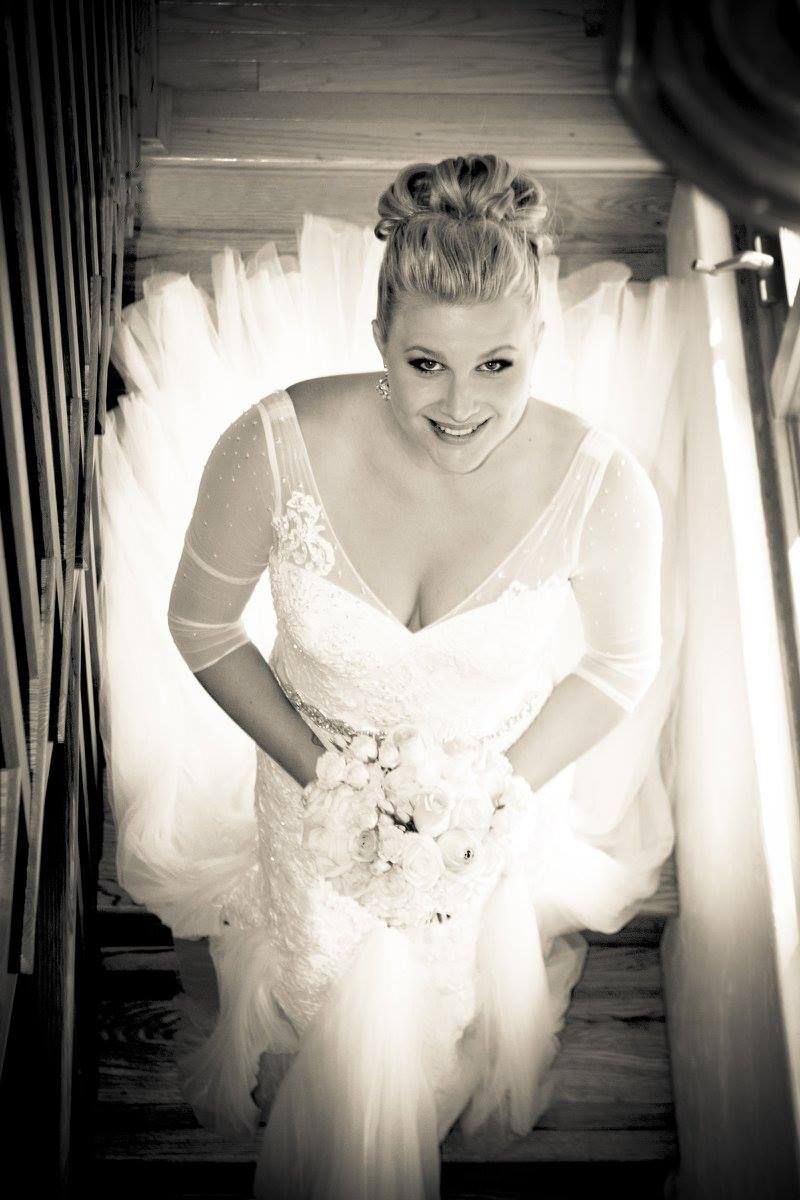 Looking up at bride standing on staircase in white wedding gown with lace details.
Wedding photography