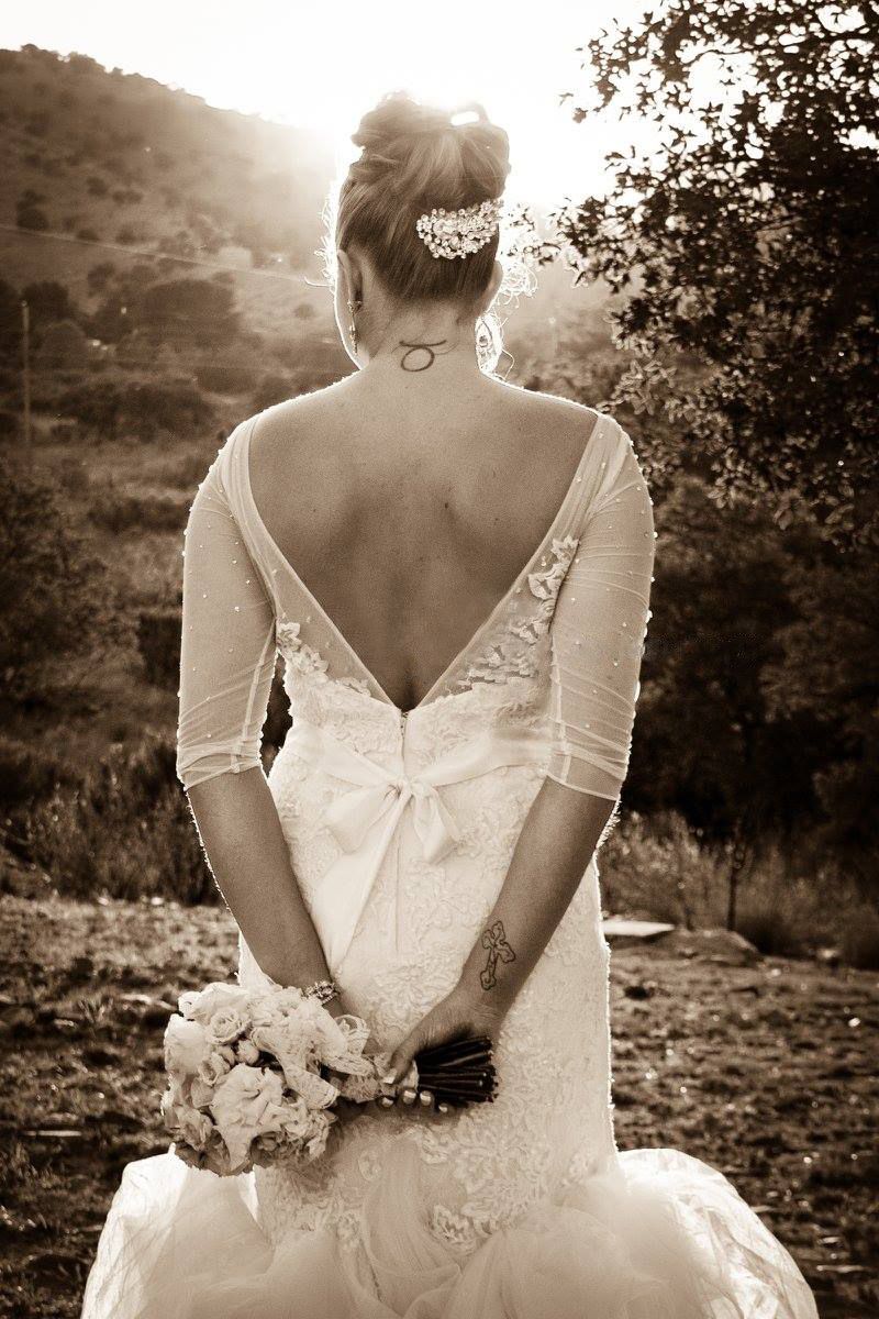 Back view of bride in lace wedding dress holding bouquet against mountainous backdrop at sunset.
Wedding photography