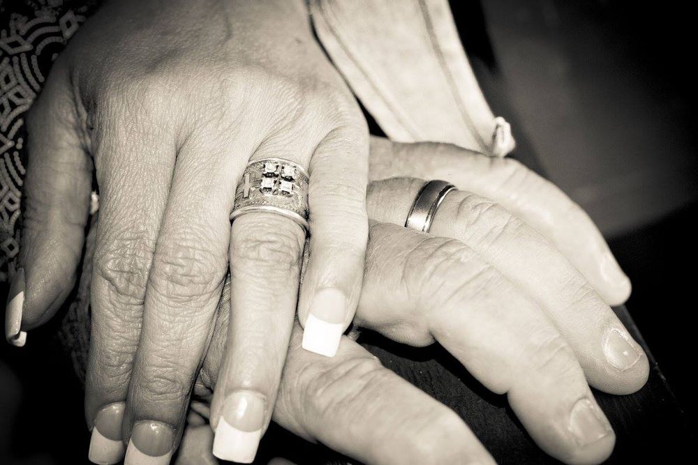 Black and white photo showing wedding rings on couple's joined hands.
Wedding photography