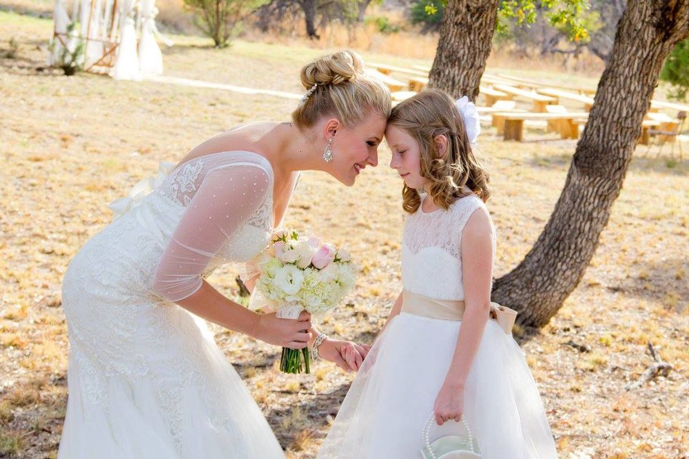 Tender moment shared outdoors between bride and flower girl during wedding ceremony.
Wedding photography