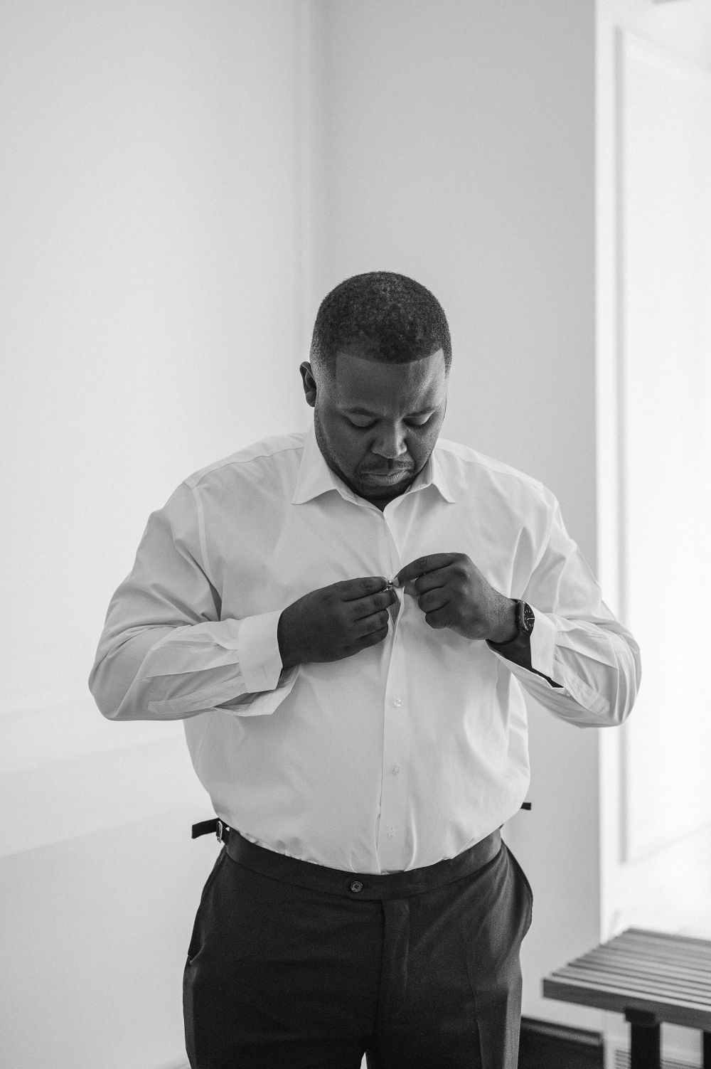 Person in white dress shirt adjusting cuffs during formal dressing preparation.