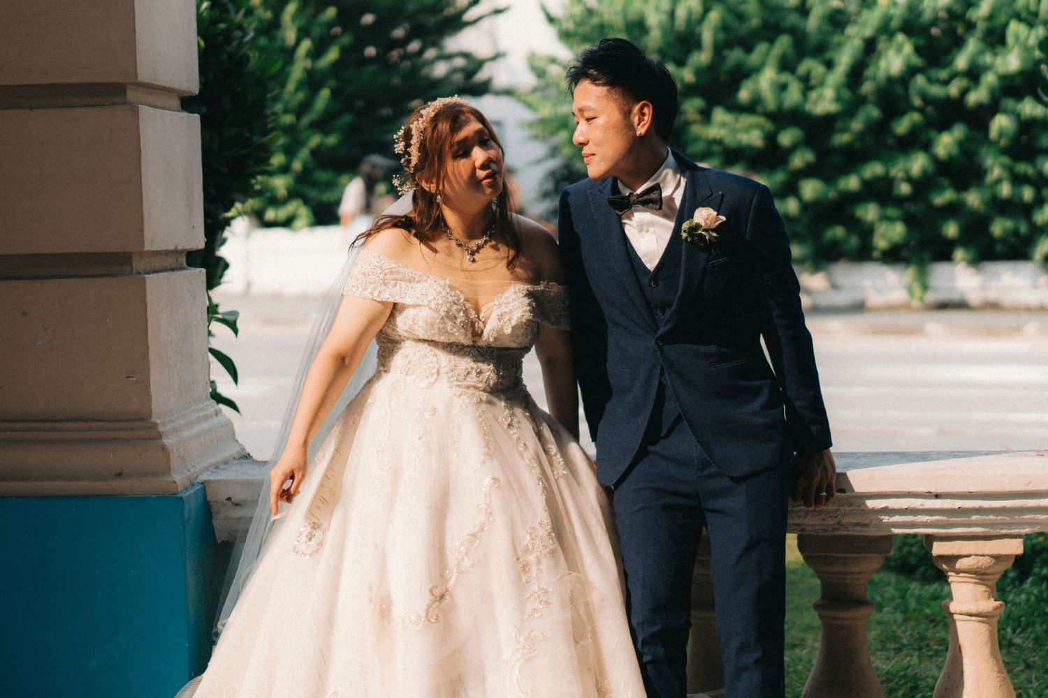 Romantic wedding couple posing under outdoor colonnade.