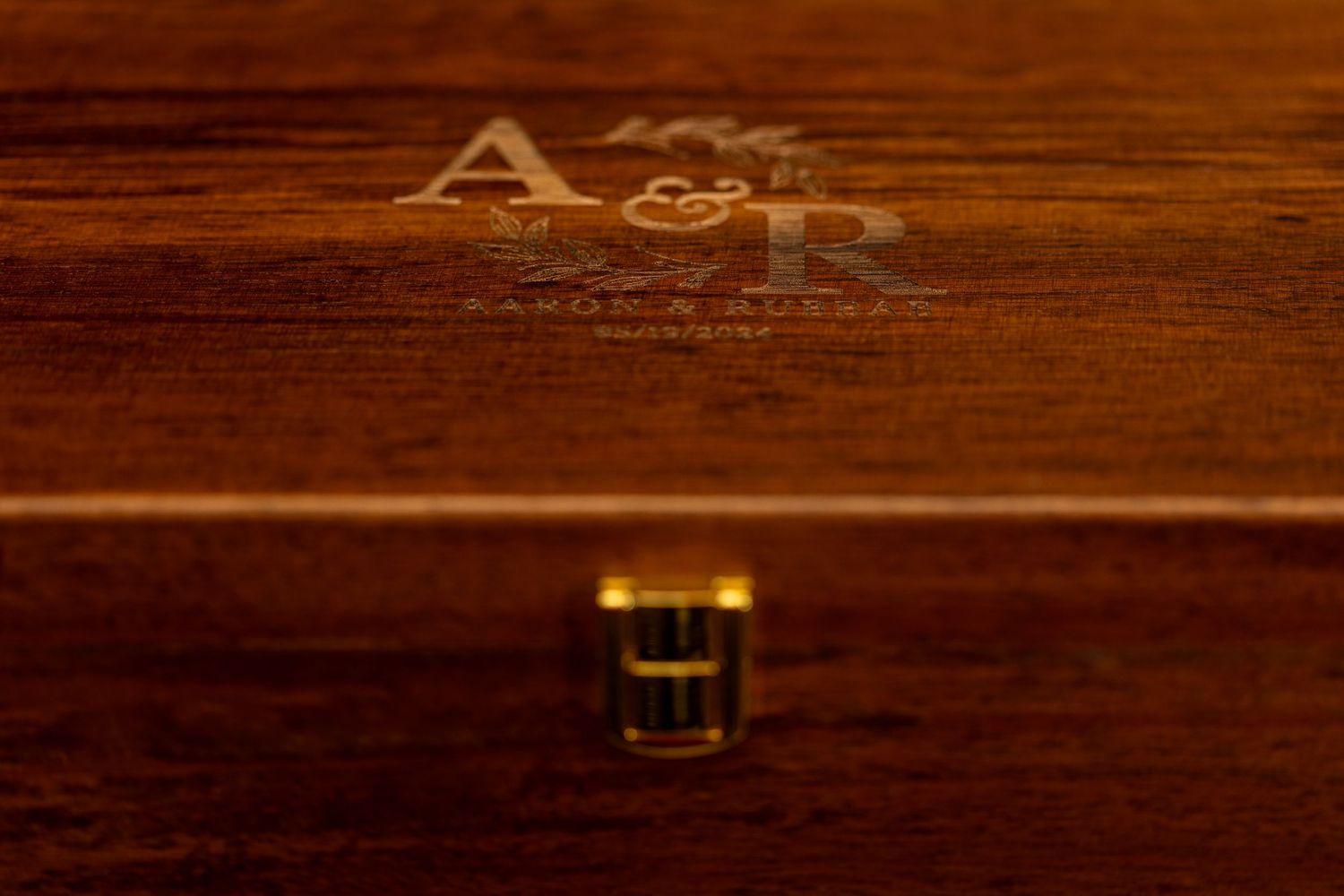 Close-up of an engraved A&R monogram on dark wooden surface.