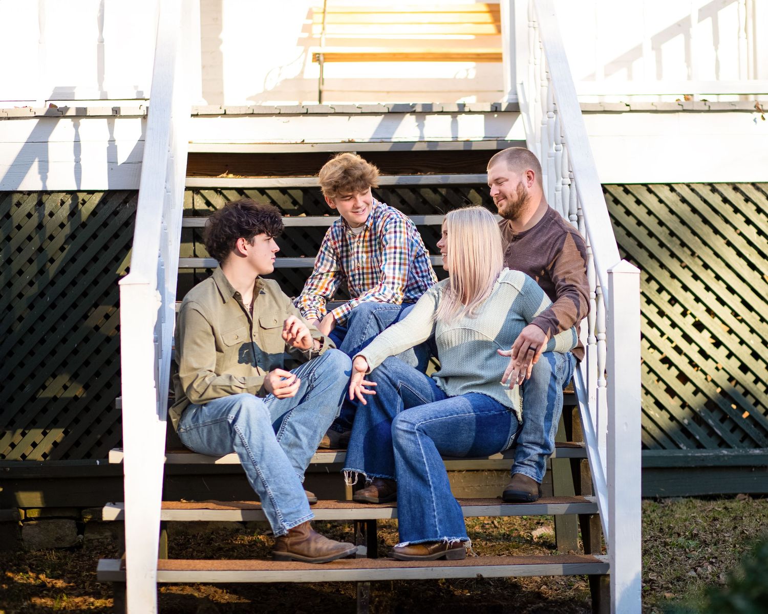 Group of friends relaxing and chatting on outdoor wooden stairs.